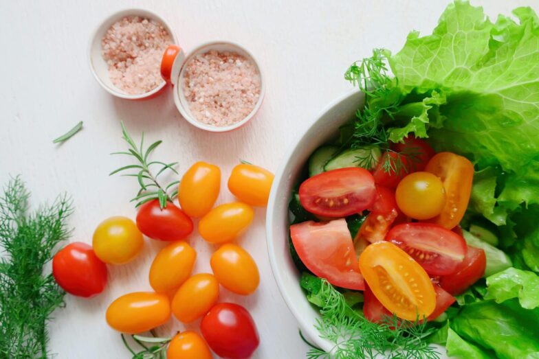 A vibrant assortment of fresh salad ingredients including tomatoes, lettuce, and Himalayan salt.