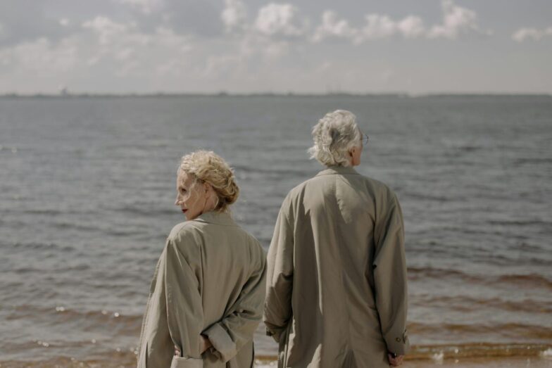 A senior couple in trench coats enjoying a tranquil day by the sea, gazing at the ocean horizon.