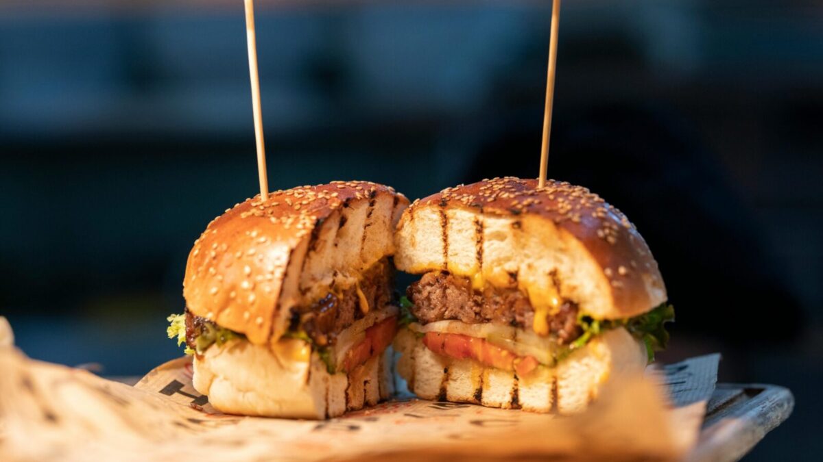 Close-up of a gourmet burger sliced in half, showcasing fresh ingredients and juicy details.