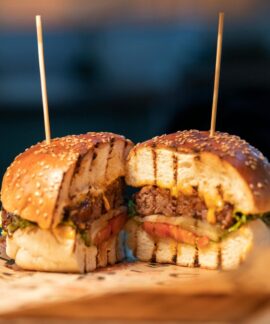Close-up of a gourmet burger sliced in half, showcasing fresh ingredients and juicy details.