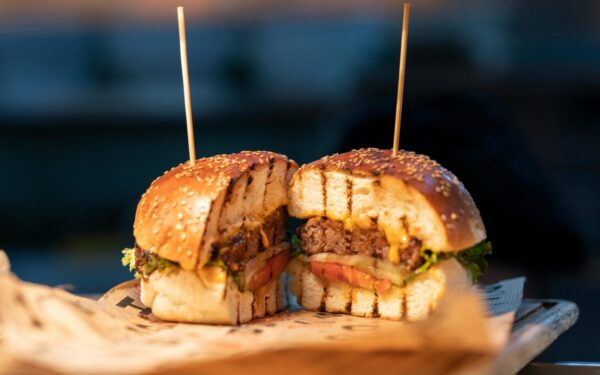 Close-up of a gourmet burger sliced in half, showcasing fresh ingredients and juicy details.