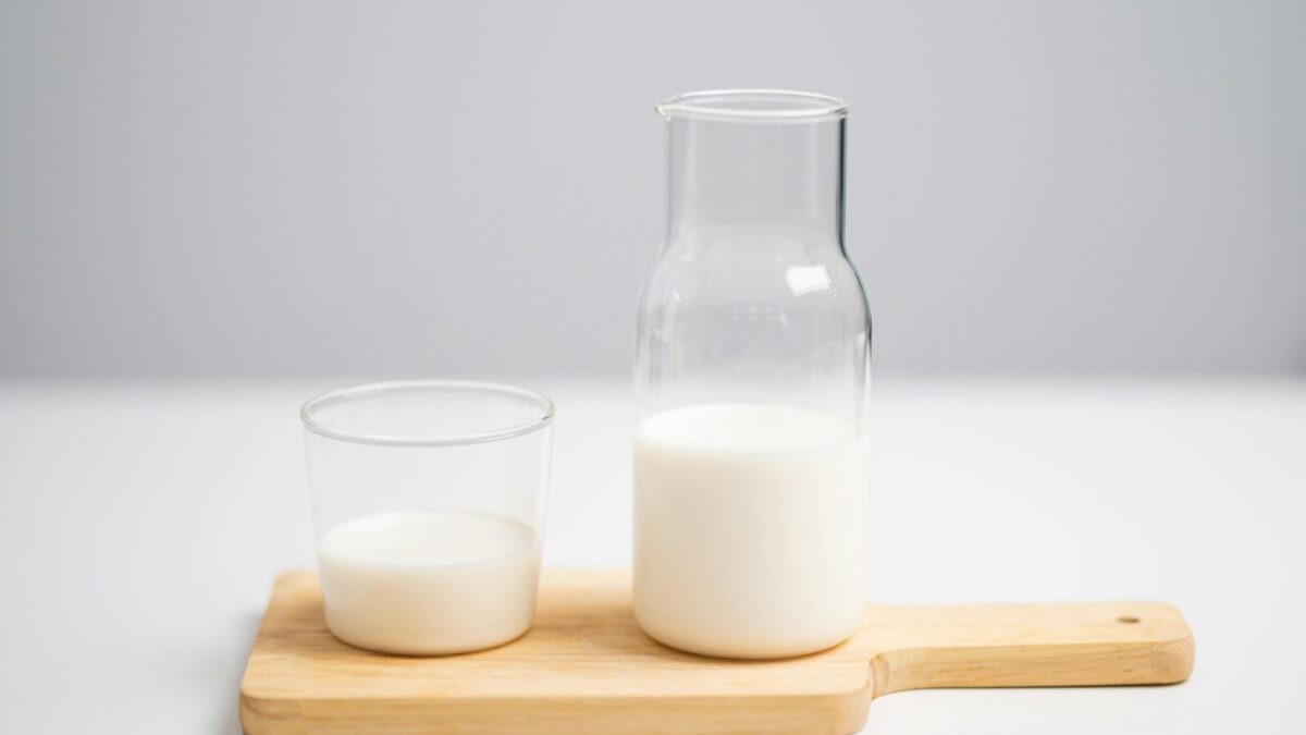 A minimalist image of milk in a glass and pitcher on a wooden board for a fresh, modern look.