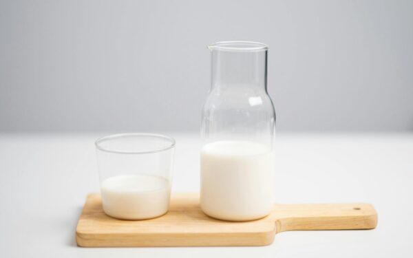 A minimalist image of milk in a glass and pitcher on a wooden board for a fresh, modern look.