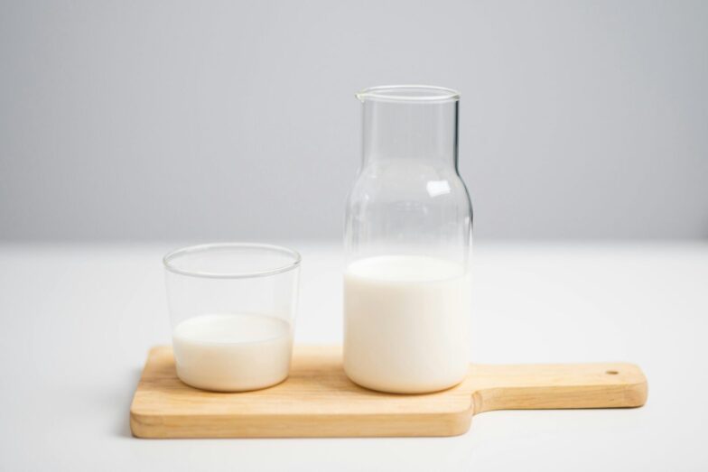 A minimalist image of milk in a glass and pitcher on a wooden board for a fresh, modern look.