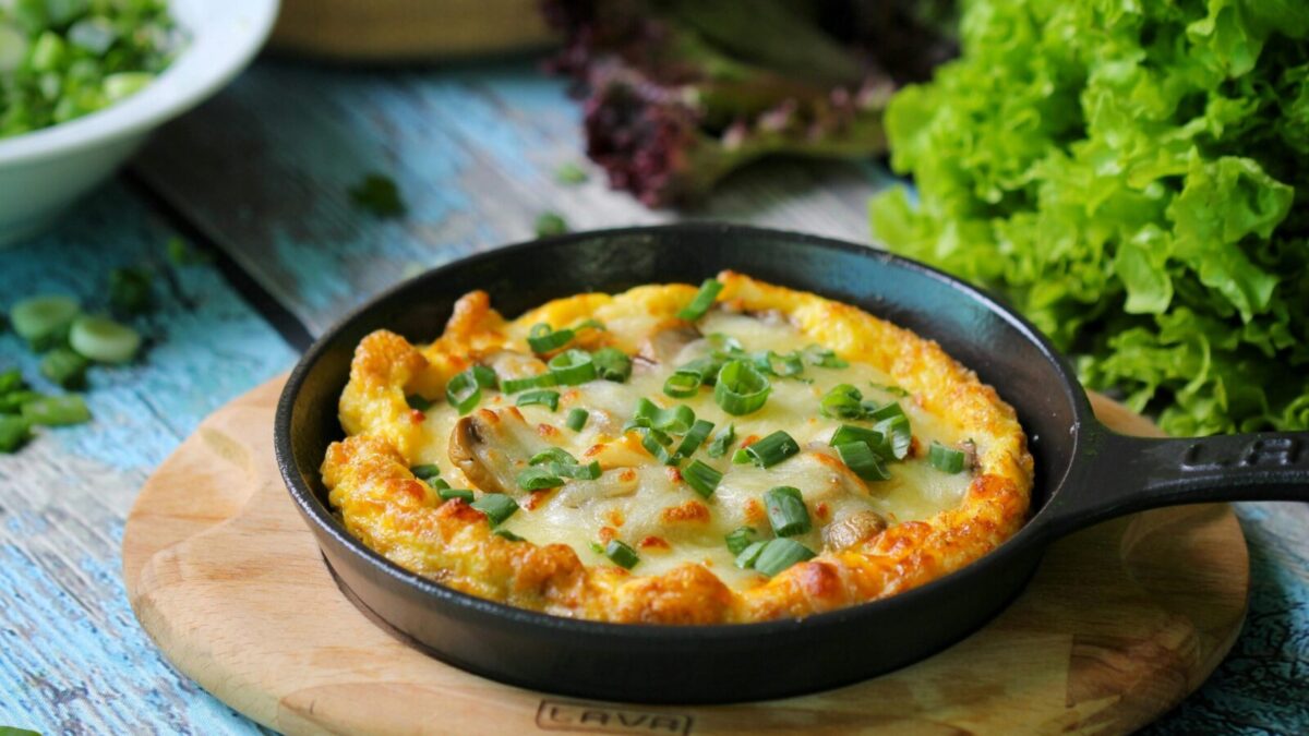 Appetizing vegetable frittata in a skillet on a rustic table with fresh greens. Perfect for brunch ideas.