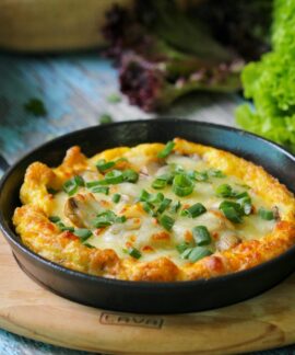 Appetizing vegetable frittata in a skillet on a rustic table with fresh greens. Perfect for brunch ideas.