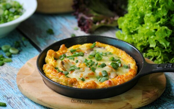 Appetizing vegetable frittata in a skillet on a rustic table with fresh greens. Perfect for brunch ideas.