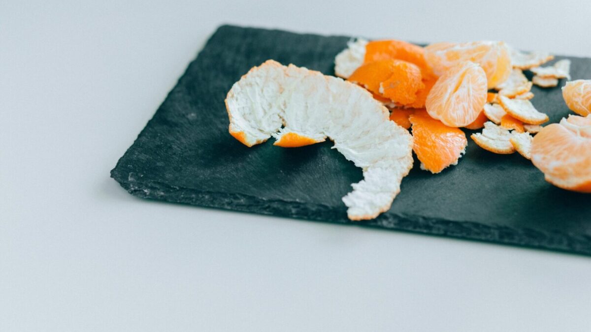 Close-up of peeled mandarins on a dark slate board, displaying freshness and vibrant color.