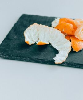 Close-up of peeled mandarins on a dark slate board, displaying freshness and vibrant color.