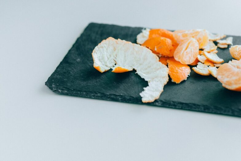 Close-up of peeled mandarins on a dark slate board, displaying freshness and vibrant color.