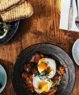 Top view of a delightful brunch spread featuring poached eggs and lattes on a wooden table.