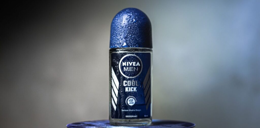 Close-up of Nivea Men Cool Kick deodorant with water droplets on a blurred background.