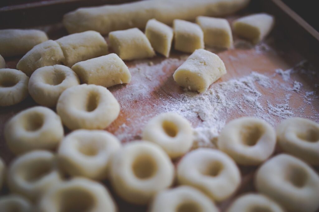A detailed view of homemade Silesian dumplings on a floured wooden board, ready for cooking.