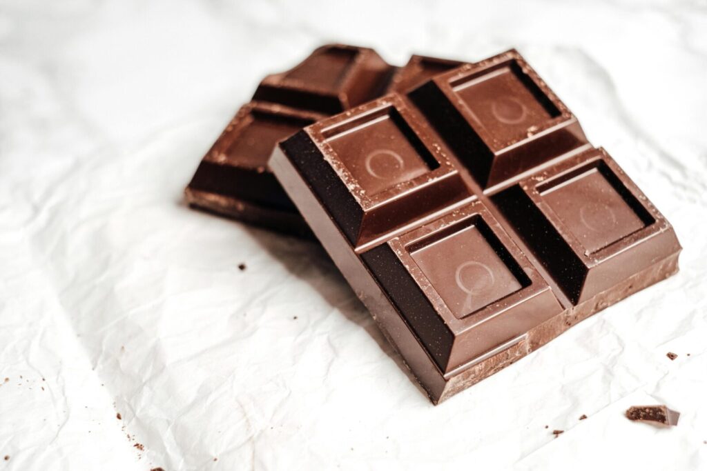Delicious dark chocolate bars showcased in a close-up shot on white paper, emphasizing texture and detail.