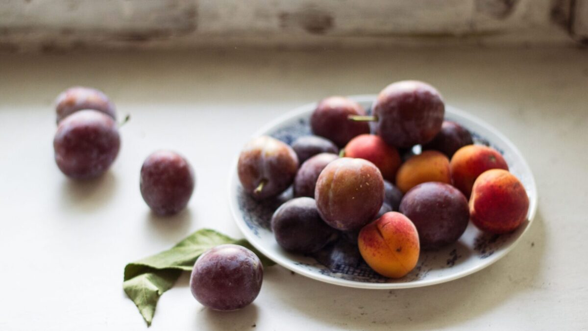 Vibrant plums arranged on a plate, capturing raw and natural beauty.