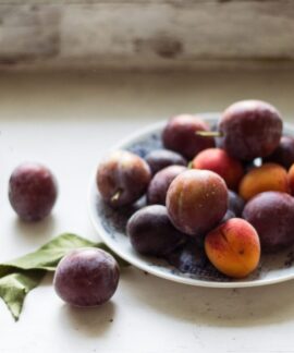 Vibrant plums arranged on a plate, capturing raw and natural beauty.