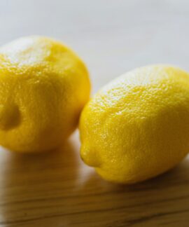 Ripe sour whole lemons placed on wooden surface in light room in kitchen with sunlight at home during harvest season