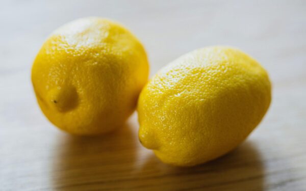 Ripe sour whole lemons placed on wooden surface in light room in kitchen with sunlight at home during harvest season