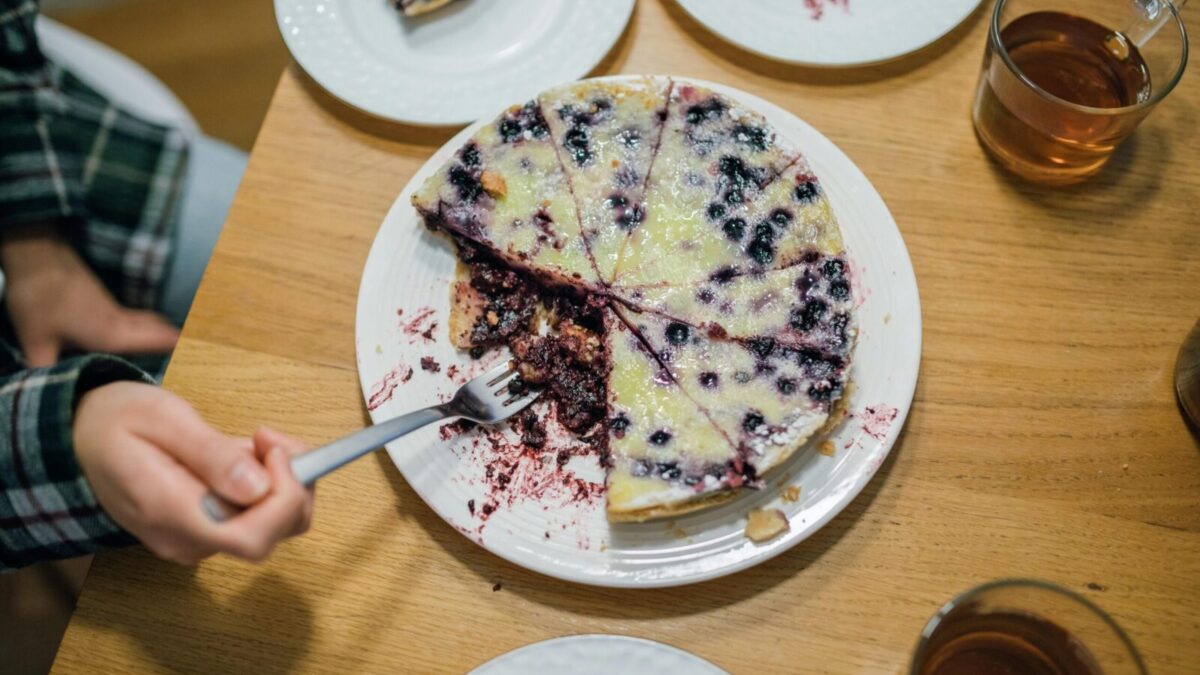 A delicious homemade blueberry pie with a fork held by a hand, perfect for dessert lovers.
