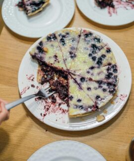 A delicious homemade blueberry pie with a fork held by a hand, perfect for dessert lovers.