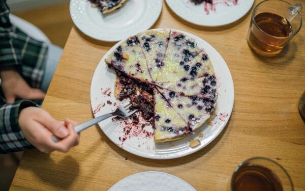 A delicious homemade blueberry pie with a fork held by a hand, perfect for dessert lovers.