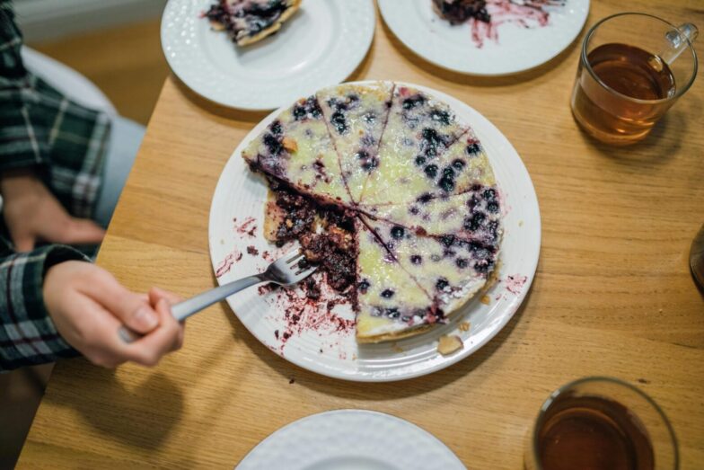 A delicious homemade blueberry pie with a fork held by a hand, perfect for dessert lovers.