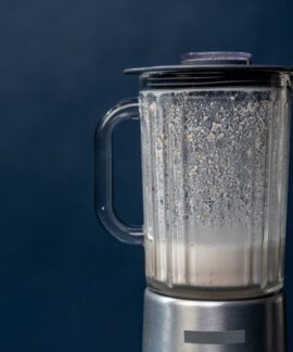 Close-up of a silver blender making a milkshake against a blue background, studio shot.