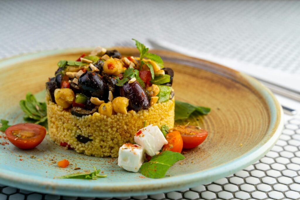 Delicious couscous salad with olives, chickpeas, and cherry tomatoes on a modern plate.
