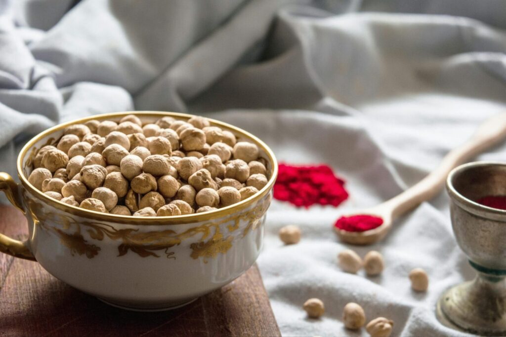 Close-up of a decorative bowl filled with chickpeas, surrounded by spices, creating a rustic kitchen scene.