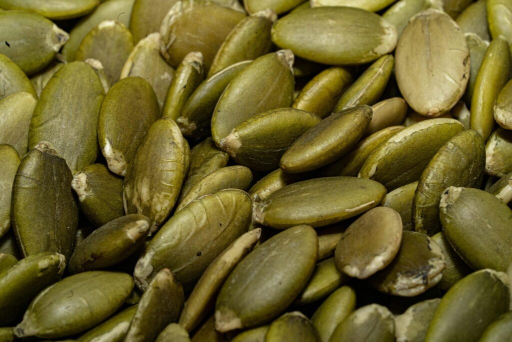 A detailed macro shot of a pile of fresh green pumpkin seeds, perfect for healthy eating concepts.