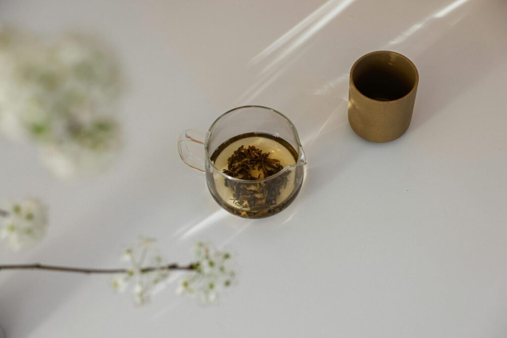 Glass cup of herbal tea and flowers in a serene minimalist setting.