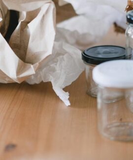 High angle of used empty glass jars with lids placed near creased paper for trash recycling