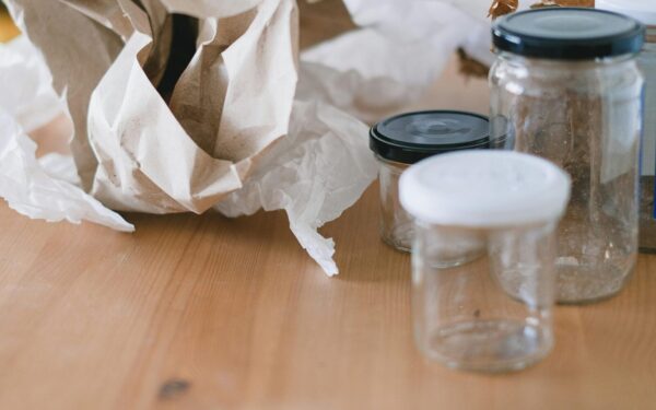 High angle of used empty glass jars with lids placed near creased paper for trash recycling