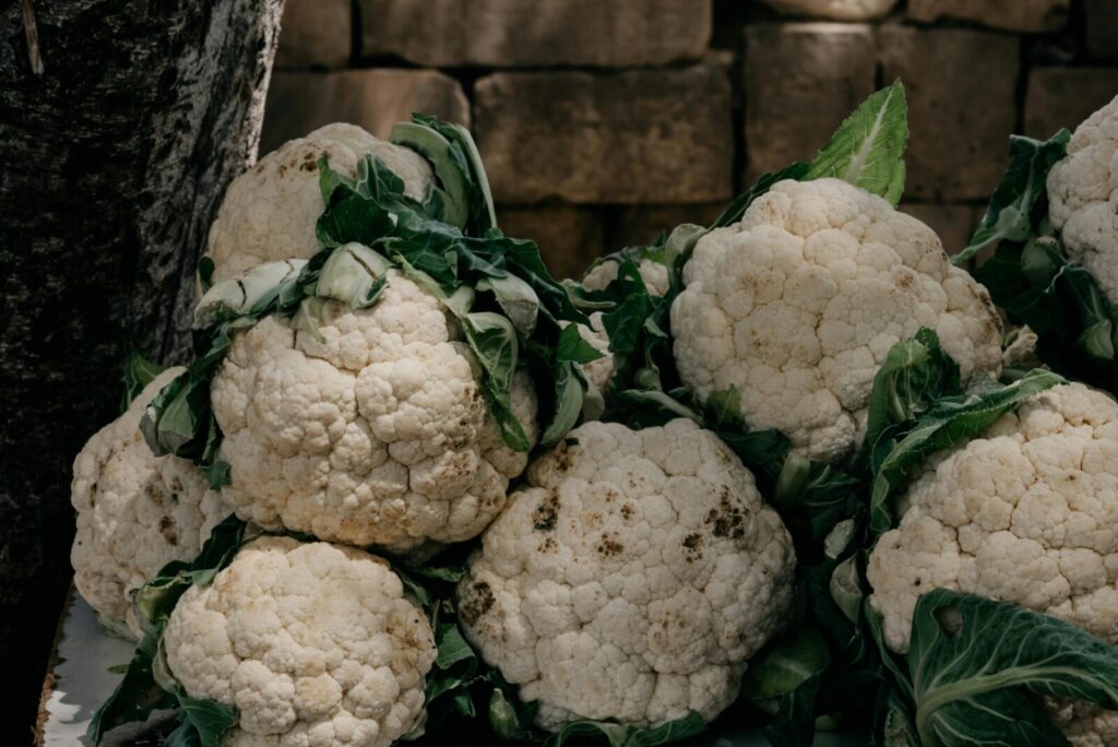 A close-up of fresh and raw organic cauliflowers with leaves, perfect for healthy cooking.