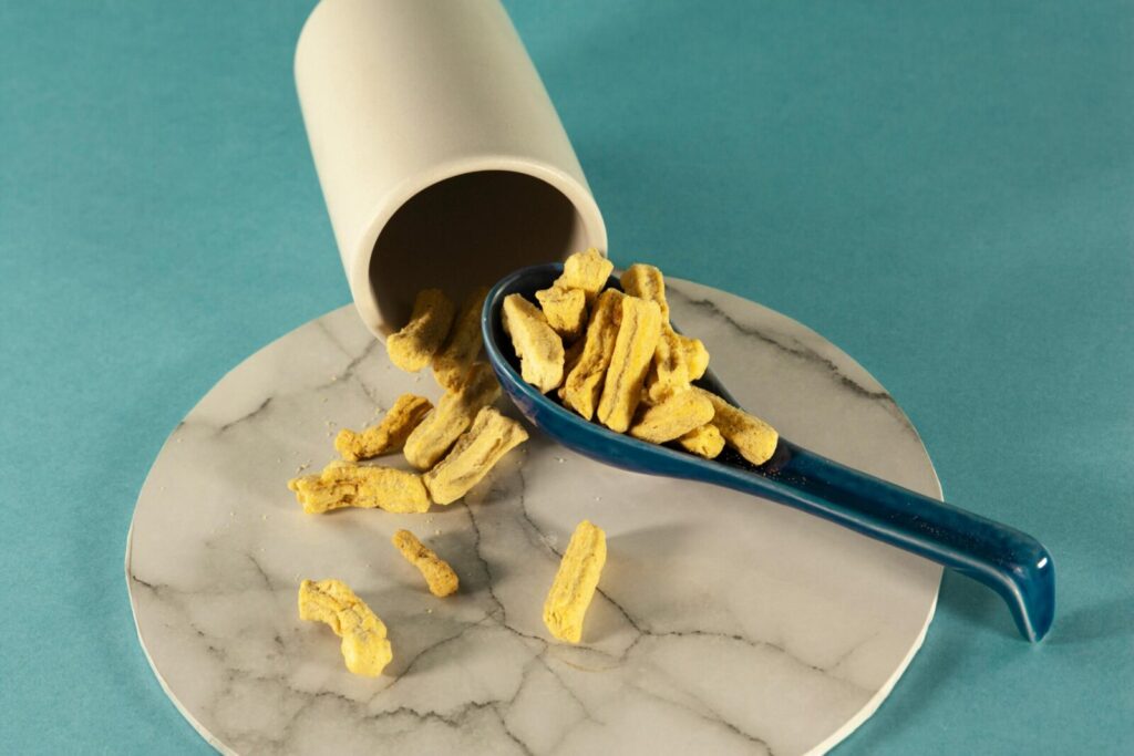 Close-up of dry chips spilled on a marble surface with a blue ceramic spoon.
