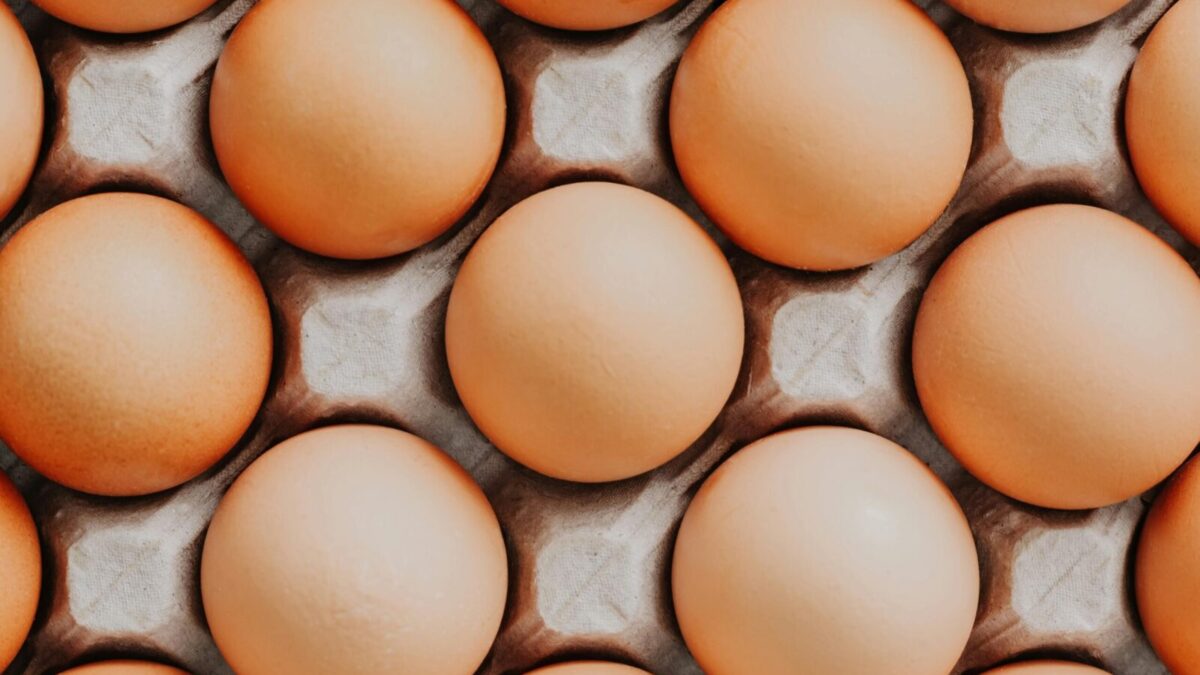 Overhead view of fresh brown eggs neatly arranged in a carton, showcasing their natural texture.