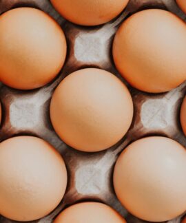 Overhead view of fresh brown eggs neatly arranged in a carton, showcasing their natural texture.