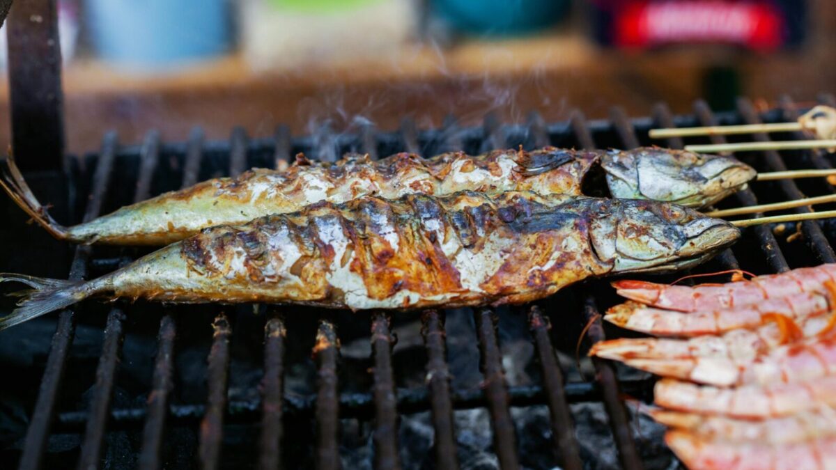 Close-up of grilled fish and shrimp cooking on an outdoor barbecue, showcasing delicious seafood options.