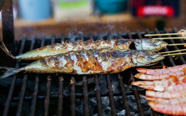 Close-up of grilled fish and shrimp cooking on an outdoor barbecue, showcasing delicious seafood options.