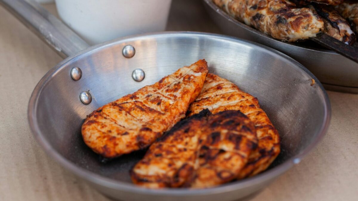 Delicious seasoned chicken breasts grilled and served in a stainless steel pan.