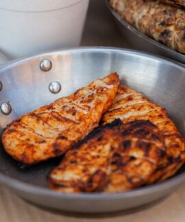 Delicious seasoned chicken breasts grilled and served in a stainless steel pan.