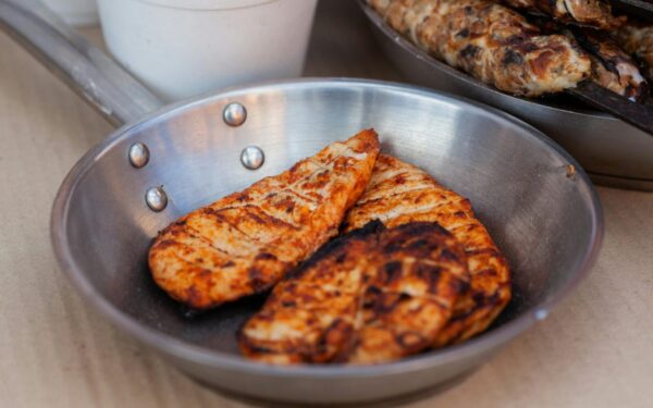 Delicious seasoned chicken breasts grilled and served in a stainless steel pan.