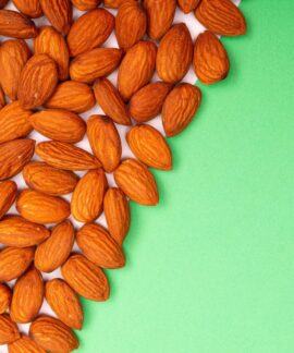 Close-up of organic almonds scattered on a green background, ideal for healthy eating concepts.