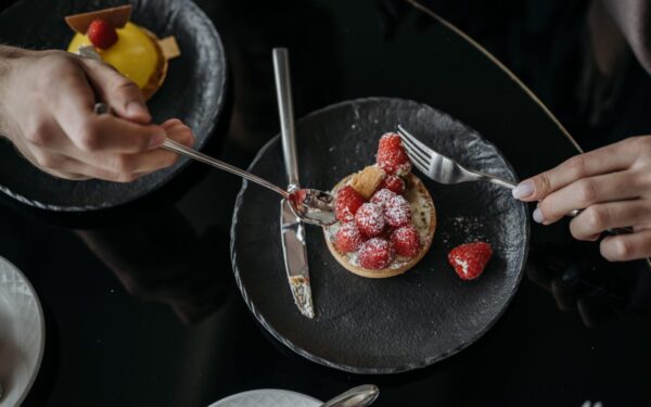 Close-up of a raspberry tart with powdered sugar on a black plate, top view.