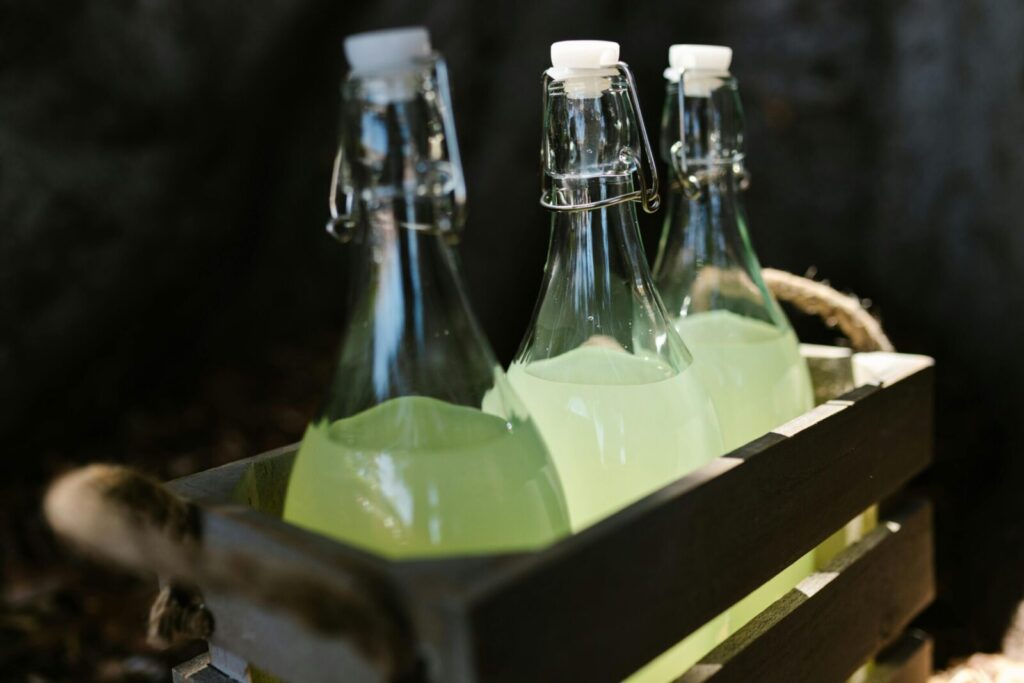 Close-up of glass bottles filled with lemonade in a rustic wooden crate. Perfect for summer refreshment imagery.