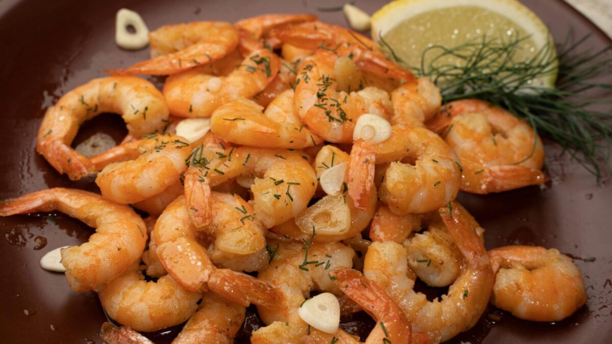 Close-up of flavorful shrimp garnished with garlic, lemon, and dill.