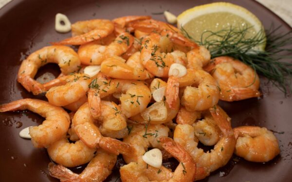Close-up of flavorful shrimp garnished with garlic, lemon, and dill.