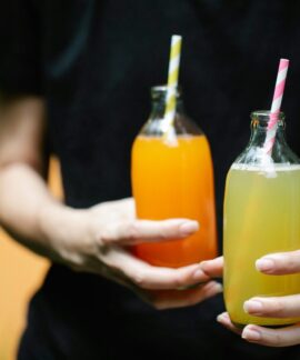 Two colorful juices in glass bottles with straws, perfect for summer refreshment.