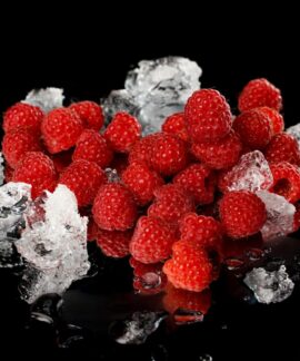 Close-up of vibrant red raspberries and melting ice on a reflective black surface.