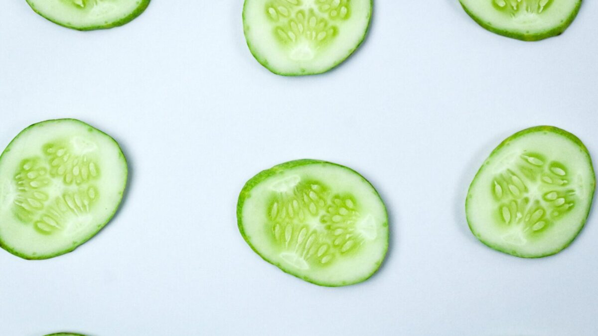 Close-up of fresh cucumber slices in a flatlay pattern on a white background.